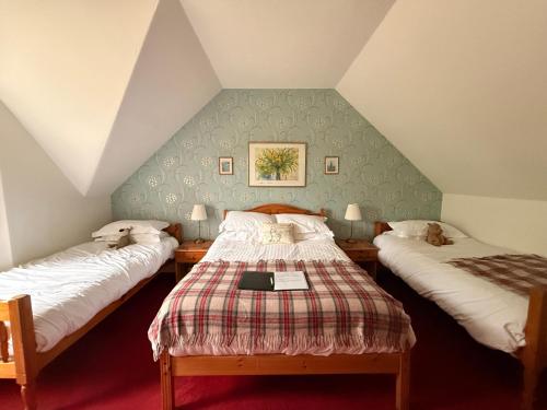 a attic room with two beds and a table at Glenan Lodge Self Catering in Tomatin