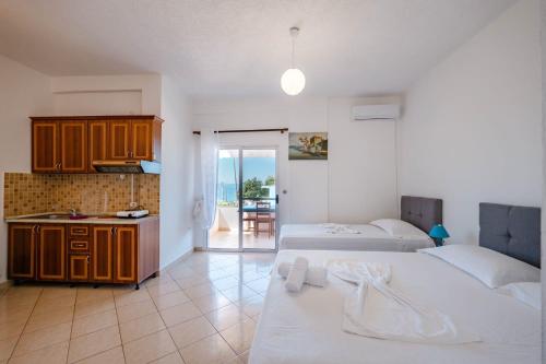 a bedroom with two beds and a kitchen with a balcony at Nefeli apartments in Borsh
