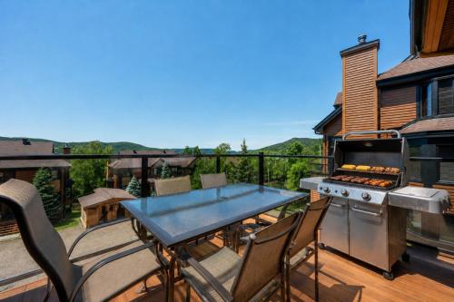 a patio with a grill and a table on a deck at Tremblant Prestige - Clairiere 406 in Mont-Tremblant