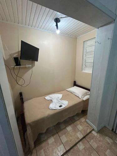 a room with a bed with a tv on the wall at Pousada Tia Leonor in Gramado