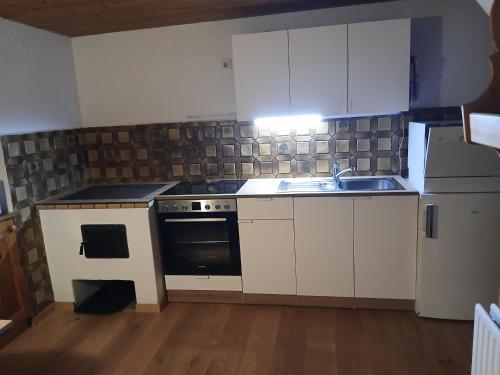 a kitchen with white cabinets and a stove and a sink at Haus am Wörtherberg in Rauris