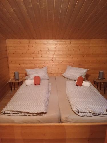 two beds in a wooden room with two tables at Haus am Wörtherberg in Rauris