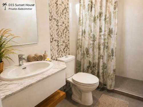 a bathroom with a sink and a toilet and a shower curtain at Oceanside Place in Rayong