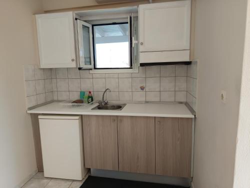 a kitchen with white cabinets and a sink at Toni´s Guesthouse in Kavos
