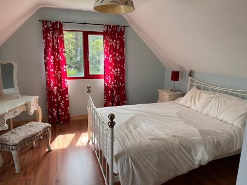 a bedroom with a bed and a window with red curtains at Callacoon Cottage in Louisburgh