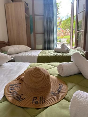 a straw hat sitting on top of two beds at Vasiliki Palli Rooms in Methana
