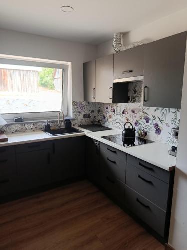 a kitchen with gray cabinets and a window and a sink at Noclegi u Kozickich in Tomaszów Lubelski