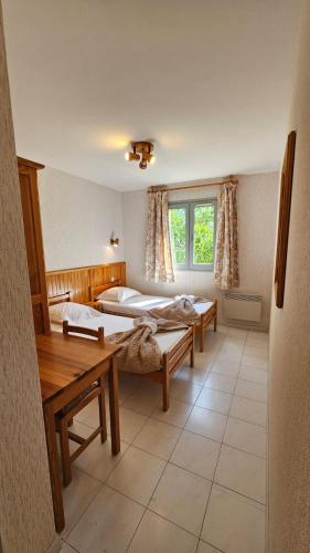 a room with two beds and a table at Auberge du Coustet in Saint-Léger
