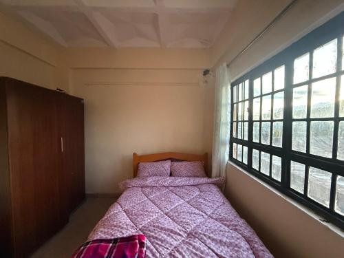 a bedroom with a bed and a large window at Arabella Homes in Maralal