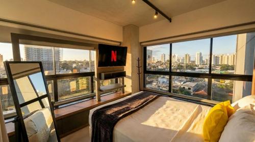 a bedroom with a large window with a view of a city at Vista Ampla e Estilo Industrial nesse Lindo Loft in Campo Grande