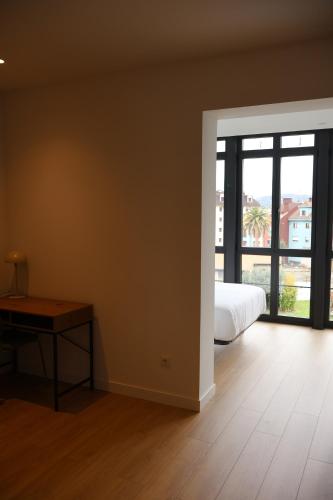 a bedroom with a bed and a table and a window at MoV Flexliving in Oviedo