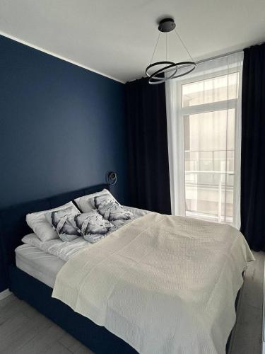 a bedroom with a bed with a blue wall and a window at Apart Premium Ku Morzu in Sianozety