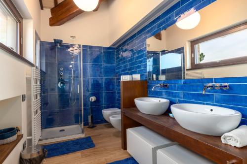 a blue tiled bathroom with two sinks and a shower at Lucciole e Lavanda BeB in Macerata