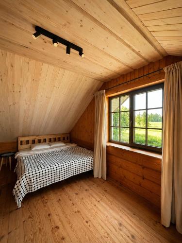 a bedroom with a bed in a room with a window at Kāpas Wood house in Uguņi