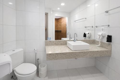 a white bathroom with a toilet and a sink at ARCUS Hotel Aracaju by ATLANTICA in Aracaju