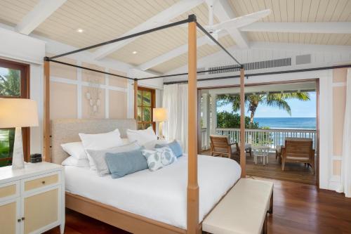 a bedroom with a bed and a balcony with the ocean at Lei Ali'i in Haleiwa