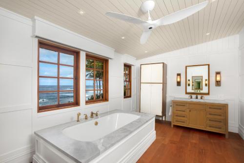 a white bathroom with a large tub and a ceiling fan at Lei Ali'i in Haleiwa