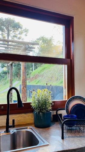 a kitchen counter with a sink and a window at Chalé Roxo na Araucária in Gonçalves