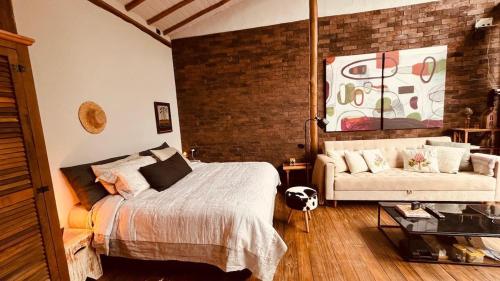 a bedroom with a bed and a couch at Chalé Roxo na Araucária in Gonçalves