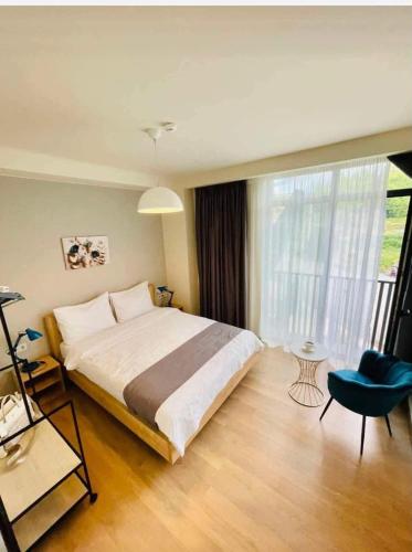 a bedroom with a large bed and a blue chair at Hotel Archi Kokhta Bakuriani Apartment 305 in Bakuriani