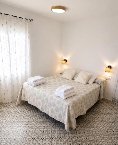 a white bedroom with a bed with towels on it at Casa Juana in Facinas