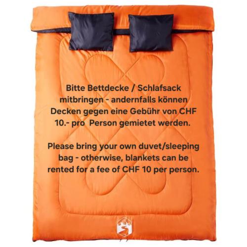 a bed with an orange comforter and a sign that reads bite bedside at Brigga Camping Mietwohnwagen in Ritzingen