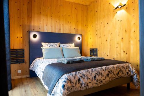 a bedroom with a large bed with wooden walls at Gîte de la Bridolée, sauna et bain nordique in Lorquin