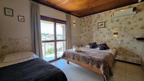 a bedroom with two beds and a window at Residencial Borges Canela in Canela