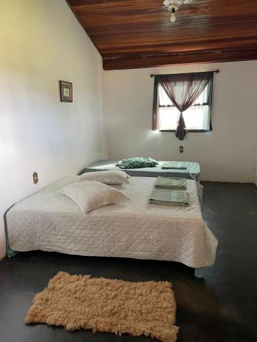 a bedroom with a large bed and a window at Pousada Canastra Raíz in Delfinópolis