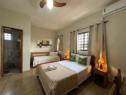 a bedroom with two beds and a ceiling fan at Chico de Sá Pousada in Pirenópolis