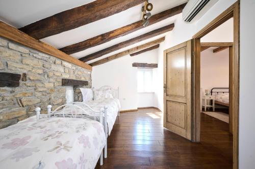 a bedroom with two beds and a stone wall at Casa Gina in Grožnjan