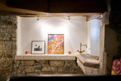 a bathroom with a stone wall with two pictures on the wall at Casa Gina in Grožnjan