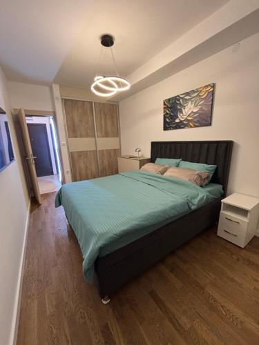 a bedroom with a bed with a green comforter at Apartman NOVA in Kragujevac