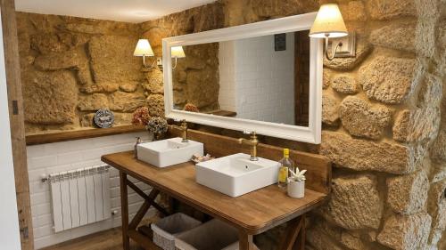 a stone bathroom with two sinks and a mirror at Finca San Román in Viascón