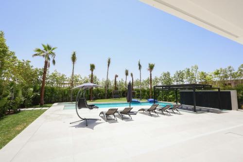 a swimming pool with chairs and an umbrella at Villa de luxe, petit déjeuner compris Golf in Marrakesh
