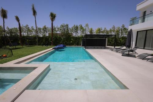 a swimming pool in a yard with palm trees at Villa de luxe, petit déjeuner compris Golf in Marrakesh