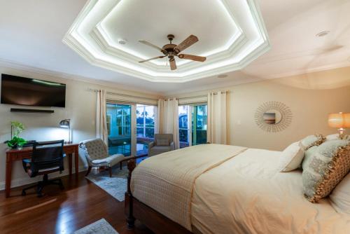 a bedroom with a ceiling fan and a desk and a bed at Villa Hibiscus-Waterfront-Free Heated Pool-Dock-Bikes-Other Amenities in Punta Gorda