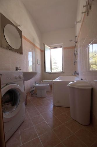 a bathroom with a toilet sink and a washing machine at Fondaco del Capo in Capo Vaticano