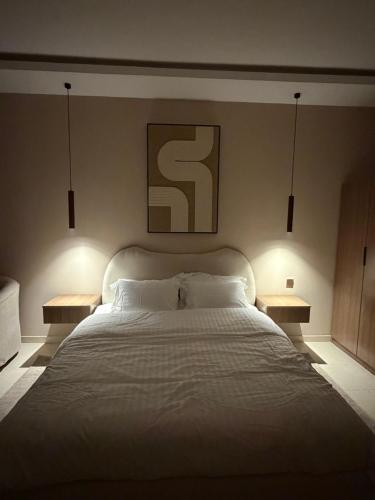 a bedroom with a large white bed with two night lights at لينك هوم استديو فندقي دخول ذاتي in Buraydah