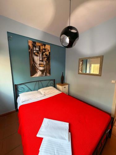 ein rotes Bett in einem Schlafzimmer mit einem Gemälde an der Wand in der Unterkunft Emily's House in Xylokastro