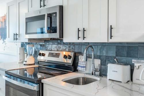 a kitchen with white cabinets and a sink and a microwave at Coastal Modern Oceanfront 2BR Yachtsman S506 in Myrtle Beach