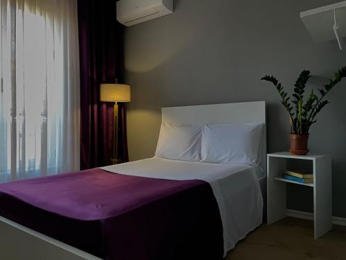 a bedroom with a bed with a purple blanket and a window at Patushe Guesthouse in Shkodër