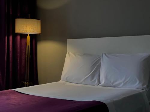 a bed with a white pillow and a lamp at Patushe Guesthouse in Shkodër