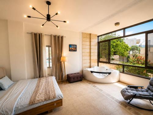 a bedroom with a tub and a large window at Zaaytre house in Ḩayy al Mukhabbaʼ