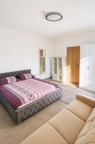 a bedroom with a large bed and a couch at Four Rooms Allgäu Apartment in Wangen im Allgäu