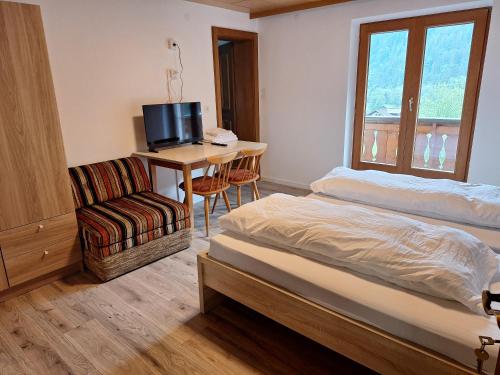 a bedroom with a bed and a desk and a chair at Montafon Valley Rooms in Sankt Gallenkirch