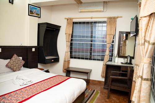 a bedroom with a bed and a desk and a window at Admire Hotel Pvt Ltd in Pokhara