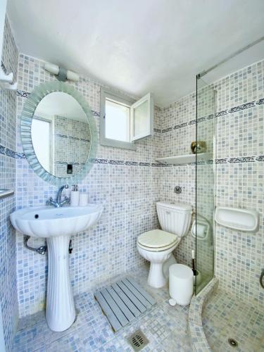 a bathroom with a sink and a toilet and a mirror at Argonaut House in Anafi