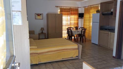 カポリーヴェリにあるBaia Azzurraのベッドルーム1室(ベッド1台付)、キッチン(テーブル付)