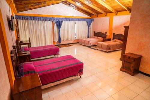 a room with three beds in a room at Hotel Tiosh Abaj in Santiago Atitlán